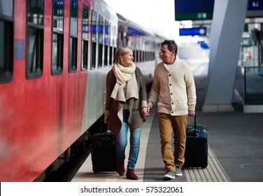 Senior couple on train station pulling trolley luggage. - Powered by Shutterstock