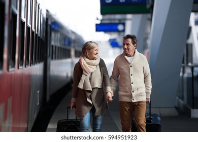 Senior couple on train station pulling trolley luggage. - Powered by Shutterstock