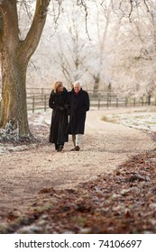 Senior Couple On Winter Walk Through Frosty Landscape