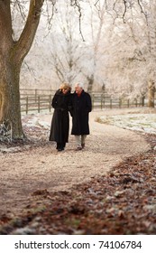 Senior Couple On Winter Walk Through Frosty Landscape