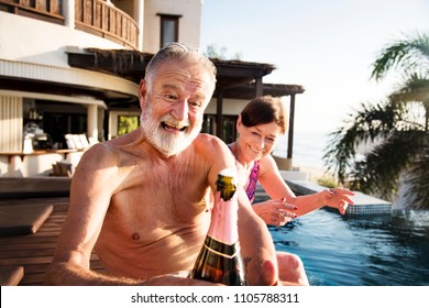 Senior couple opening a champagne bottle - Powered by Shutterstock