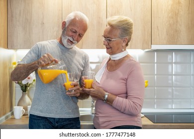 Senior couple with orange juice in the kitchen.They are standing at table in kitchen.Enjoying their time.Health care and people concept. - Powered by Shutterstock