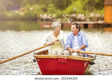 Senior Couple Paddling On Boat On Mountain Tarn