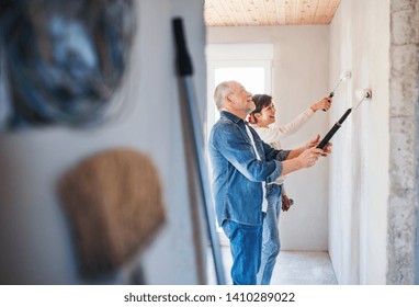 Senior Couple Painting Walls In New Home, Relocation Concept.