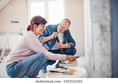 Senior Couple Painting Walls In New Home, Relocation Concept.