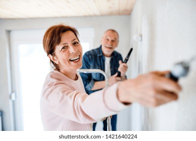 Senior Couple Painting Walls In New Home, Relocation Concept.