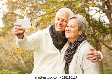 Senior couple in the park taking selfie on an autumns day - Powered by Shutterstock