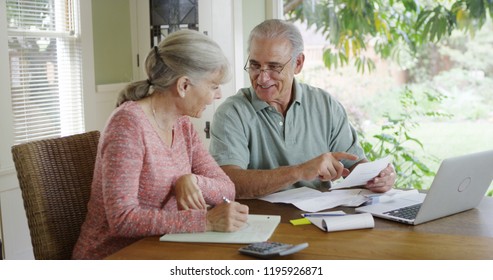 Senior Couple Paying Bills Together On Laptop