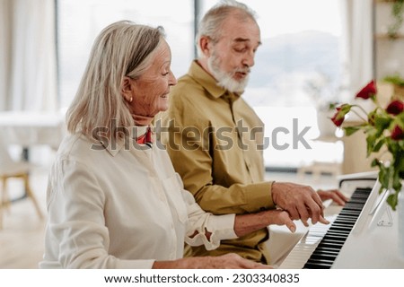 Senior couple playing on piano together at home.