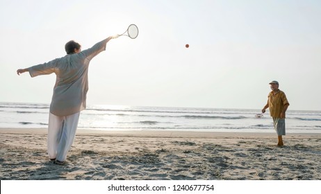 Senior couple playing tai chi ballon ball at the beach. Active leisure of aged family outdoor.
