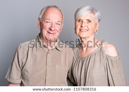 Senior couple posing on studio gray background