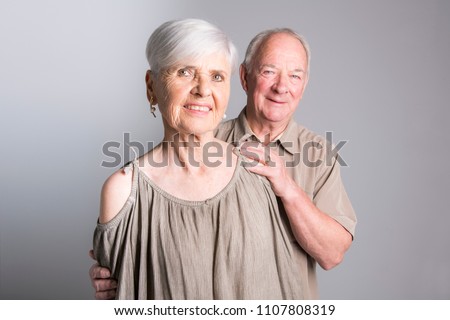 Senior couple posing on studio gray background