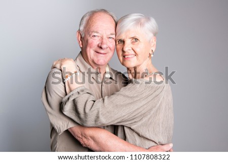 Senior couple posing on studio gray background