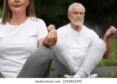 Senior couple practicing yoga outdoors, selective focus - Powered by Shutterstock