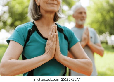 Senior couple practicing yoga together outdoors in the park selective focus on hands outdoors. Active lifestyle concept - Powered by Shutterstock