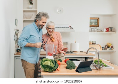 Senior couple preparing healthy smoothie in kitchen and using tablet to read recipe - Powered by Shutterstock