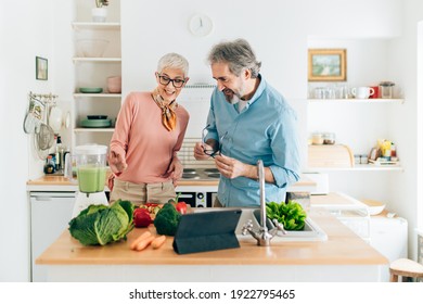 Senior couple preparing healthy smoothie in kitchen and using tablet to read recipe - Shutterstock ID 1922795465