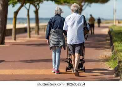 Senior Couple Pushing A Baby Stroller.