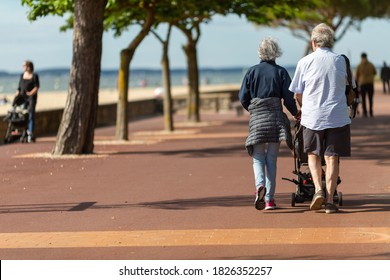 Senior Couple Pushing A Baby Stroller.