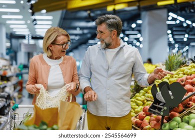 Senior couple pushing shopping cart and choosing fresh produce at grocery store, enjoying their retirement and making healthy choices together - Powered by Shutterstock