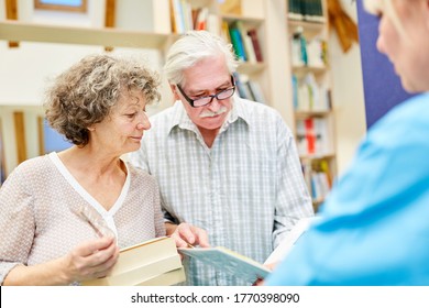 Senior Couple Reading A Book About Continuing Education In The Library At The Retirement Home