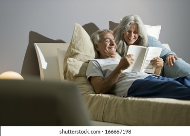 Senior Couple Reading A Book In The Bed