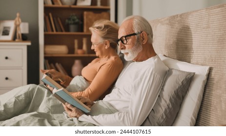 Senior couple reading books in bed - Powered by Shutterstock