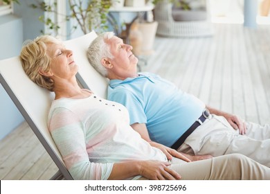 Senior couple relaxing on lounge chair at porch - Powered by Shutterstock