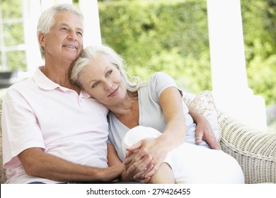 Senior Couple Relaxing On Seat Outside House