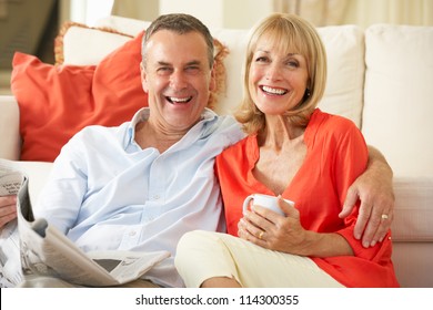 Senior Couple Relaxing On Sofa At Home Reading Newspaper - Powered by Shutterstock