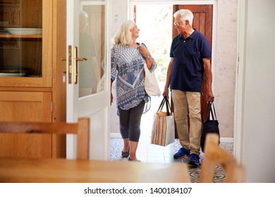 Senior Couple Returning Home From Shopping Trip Carrying Grocery Bags Through Kitchen - Powered by Shutterstock