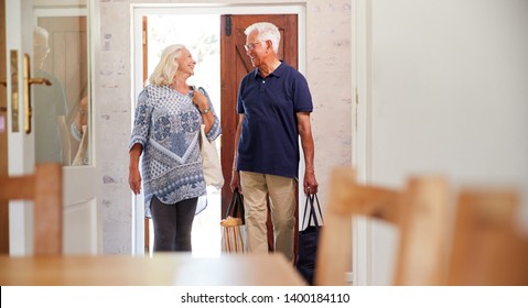 Senior Couple Returning Home From Shopping Trip Carrying Grocery Bags Through Kitchen - Powered by Shutterstock
