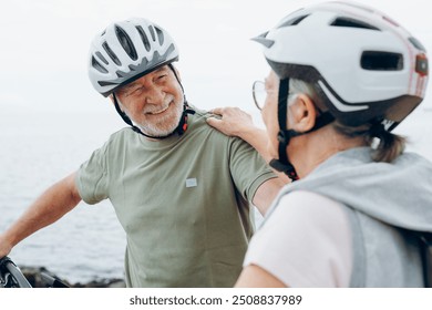 Senior couple riding bikes together in rocky beach enjoying outdoor. Active mature people talking and hugging each others. Bicycle lifestyle concept, having fun - Powered by Shutterstock