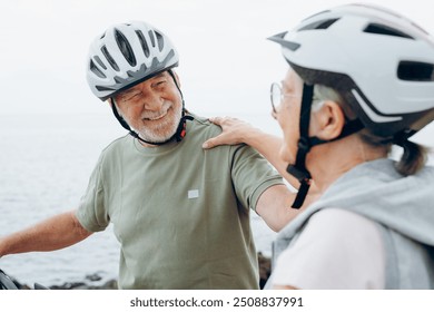 Senior couple riding bikes together in rocky beach enjoying outdoor. Active mature people talking and hugging each others. Bicycle lifestyle concept, having fun - Powered by Shutterstock