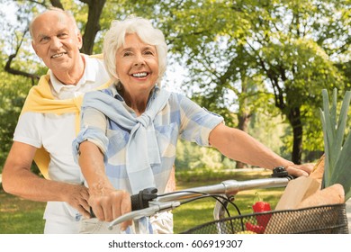 Senior Couple Riding Tandem Bike In The Park