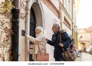 Senior Couple Ringing The Doorbell To Their Guest House