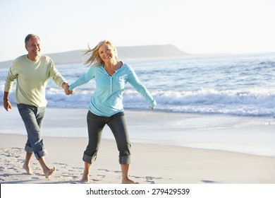 Senior Couple Running Along Beach