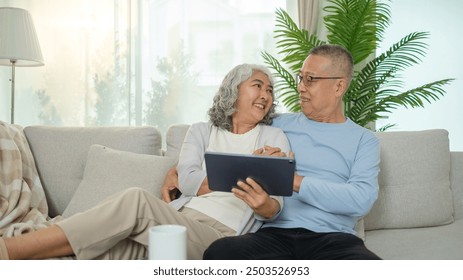 Senior couple shares a joyful moment on a cozy couch as they look into each other’s eyes with smiles. - Powered by Shutterstock