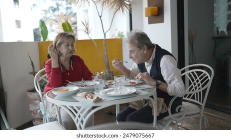 Senior Couple Sharing a Meal and Conversation on a Decorative Balcony - Powered by Shutterstock