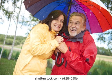 Senior Couple Sharing An Umbrella In The Rain