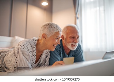 Senior couple shopping online from bed with the help of technology - Powered by Shutterstock