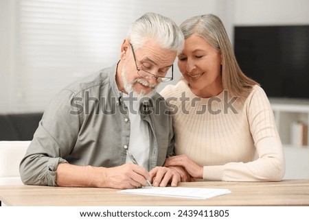 Senior couple signing Last Will and Testament indoors