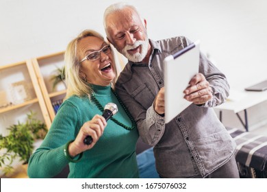 Senior couple singing karaoke at home, having fun.Quarantine. 