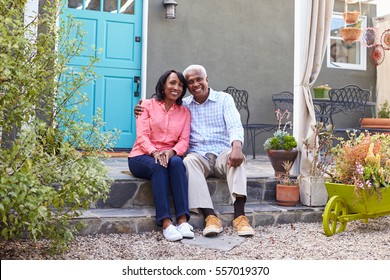 Senior Couple Sit On Steps Outside Their House, Full Length