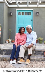 Senior Couple Sit On Steps Outside Their House, Vertical