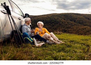 Senior couple sitting against the car, resting after hiking in countryside. - Shutterstock ID 2253362779