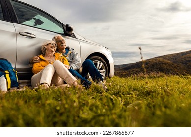 Senior couple sitting against the car, resting after hiking in countryside. - Powered by Shutterstock