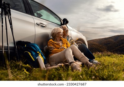 Senior couple sitting against the car, resting after hiking in countryside. - Powered by Shutterstock