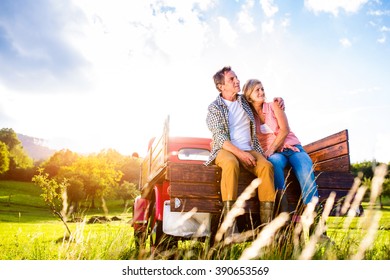 Senior Couple Sitting In Back Of Red Pickup Truck