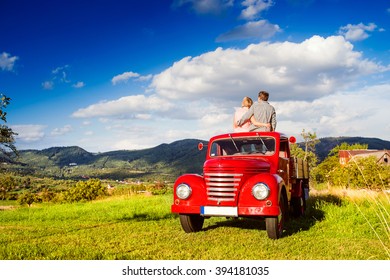 Senior Couple Sitting In Back Of Red Pickup Truck